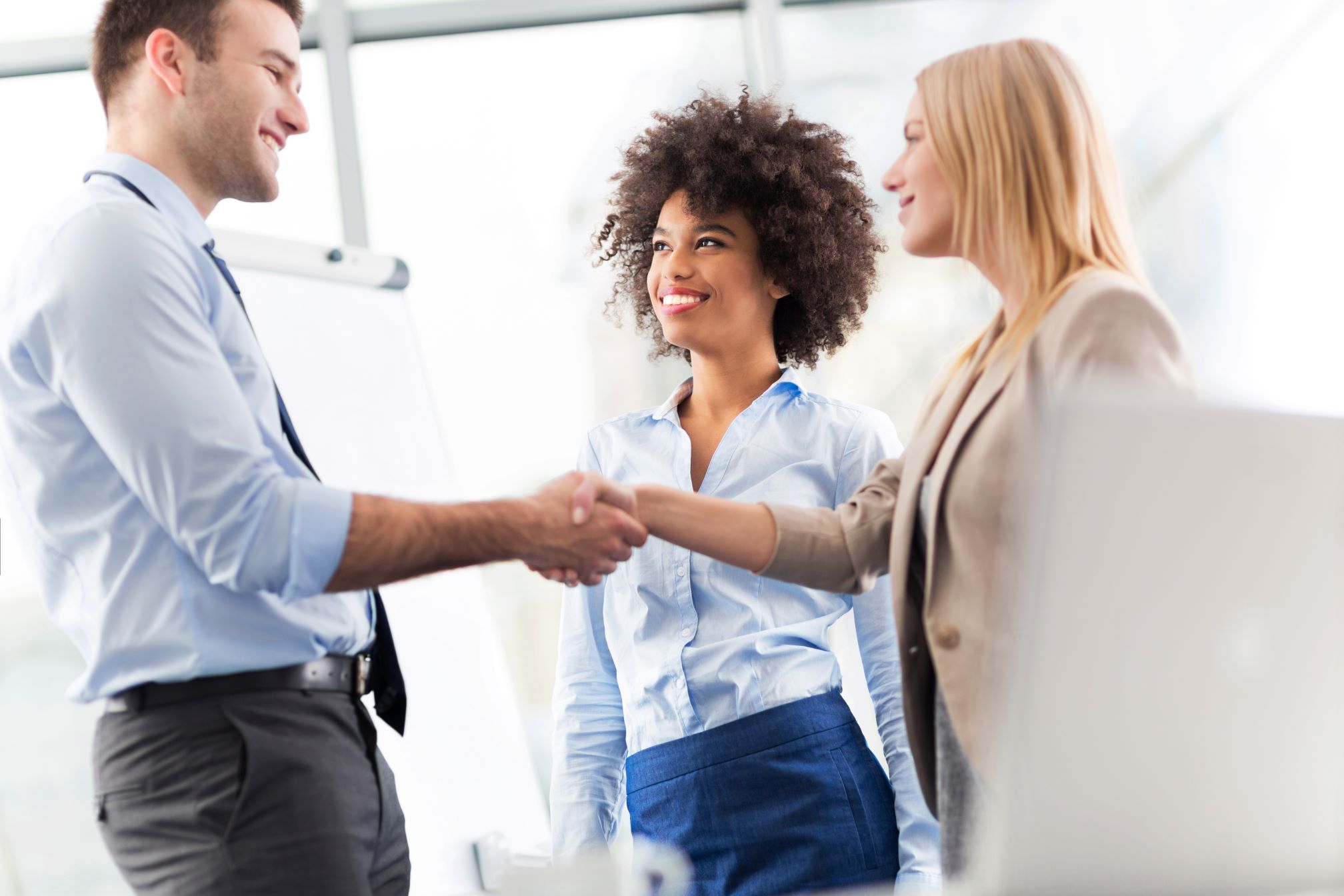 A man and two women shaking hands in a business setting