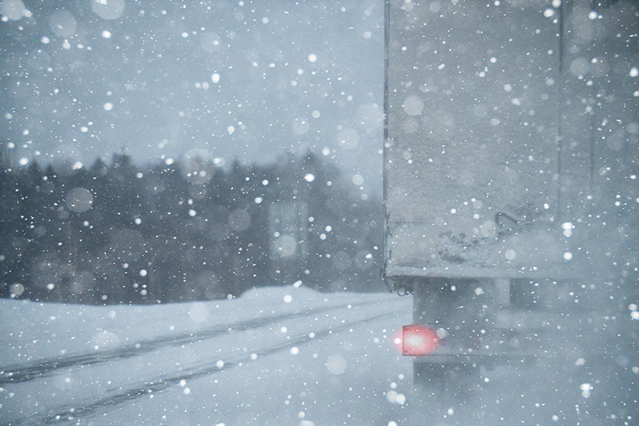 Semi truck driving through heavy snow.